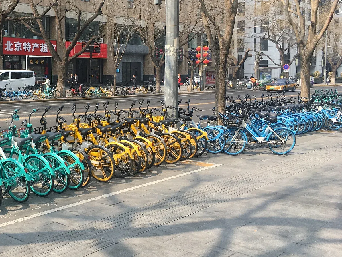中国・北京の歩道に並ぶシェア自転車。青・黄色・水色と複数の会社の自転車が街中にあふれている