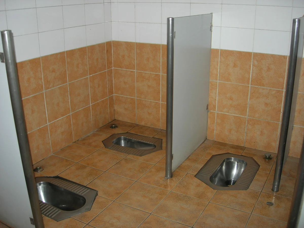 中国の公衆トイレの蹲便器。仕切りはあるが低めのタイプ